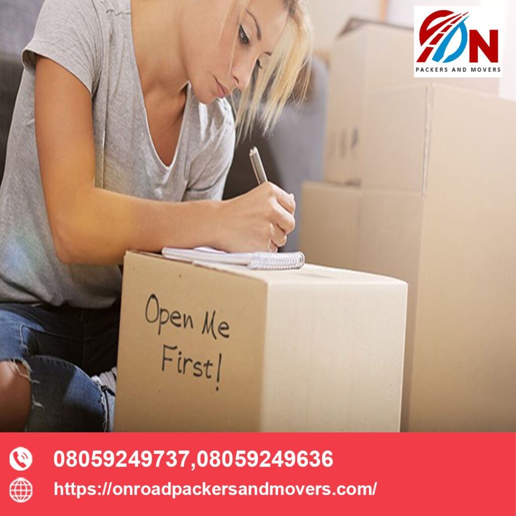 a girl writing open me on on road packers and movers in bangalore boxes so that she can identify them while opening